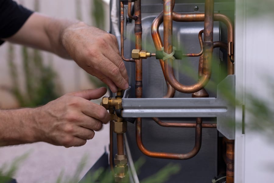 Close-up shot of an HVAC tech repairing a heat pump